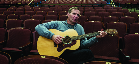 Tim Ryan Rouillier picks his guitar while chatting inside UM’s Dennison Theatre. Ryan, a country music artist in Nashville originally from tiny St. Ignatius, will debut his symphonic memoir, “Play Me Montana,” inside the same theater on June 17.